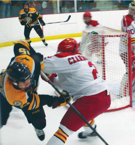 Senior defenseman Scott Czarnowczan checks a Michigan Tech offender to stop him from scoring a goal. The Bulldogs swept Michigan Tech this past weekend at home, but they face a bigger challenge when they travel to Minnesota to face off against the Mavericks on Jan. 17 and 18. Photo By: Melanie Ronquillo | Photographer