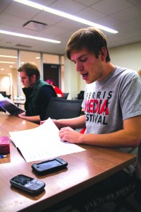 Ferris television and digital media production student Michael Hermann hums through sheet music at a rehearsal with his a capella RSO, Acaholics.