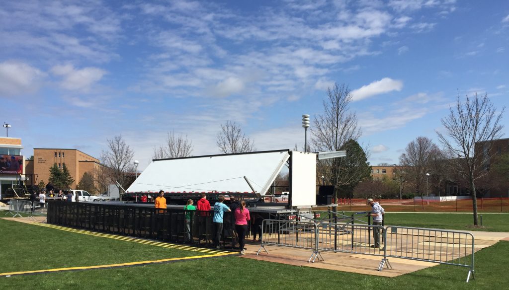 Volunteers work diligently to tear down the stage that was erected earlier today as threatening storm clouds loom in the distance.