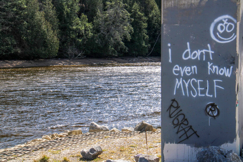 Graffiti on a cement pillar reading "i don't even know MYSELF"