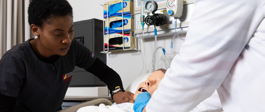 Nursing student checks the pulse of a patient simulation doll.